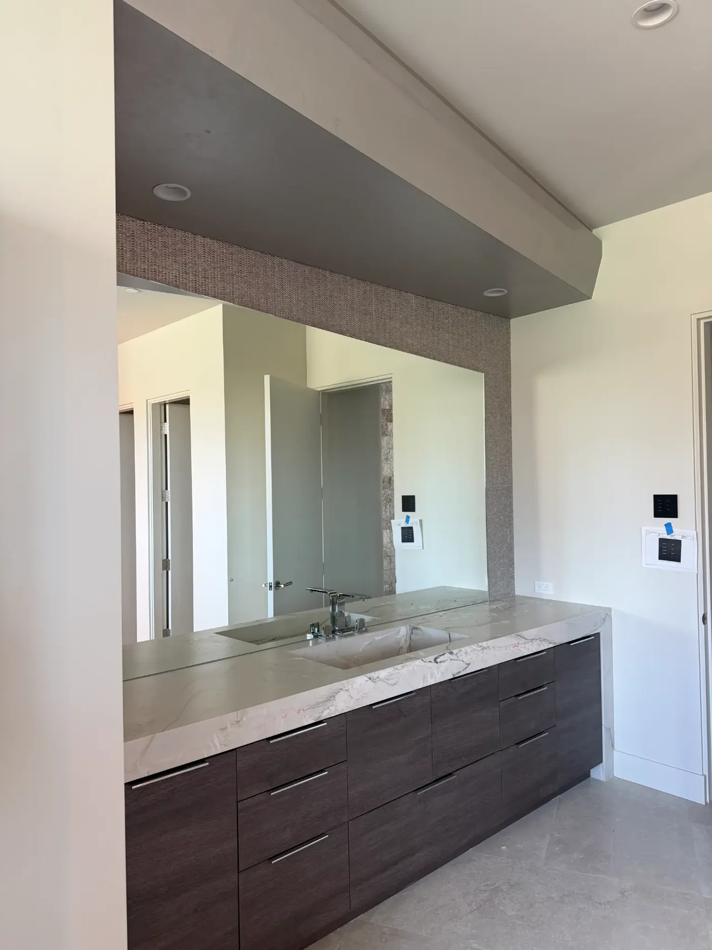 Large frameless bathroom mirror and stone vanity after post-construction glass detailing