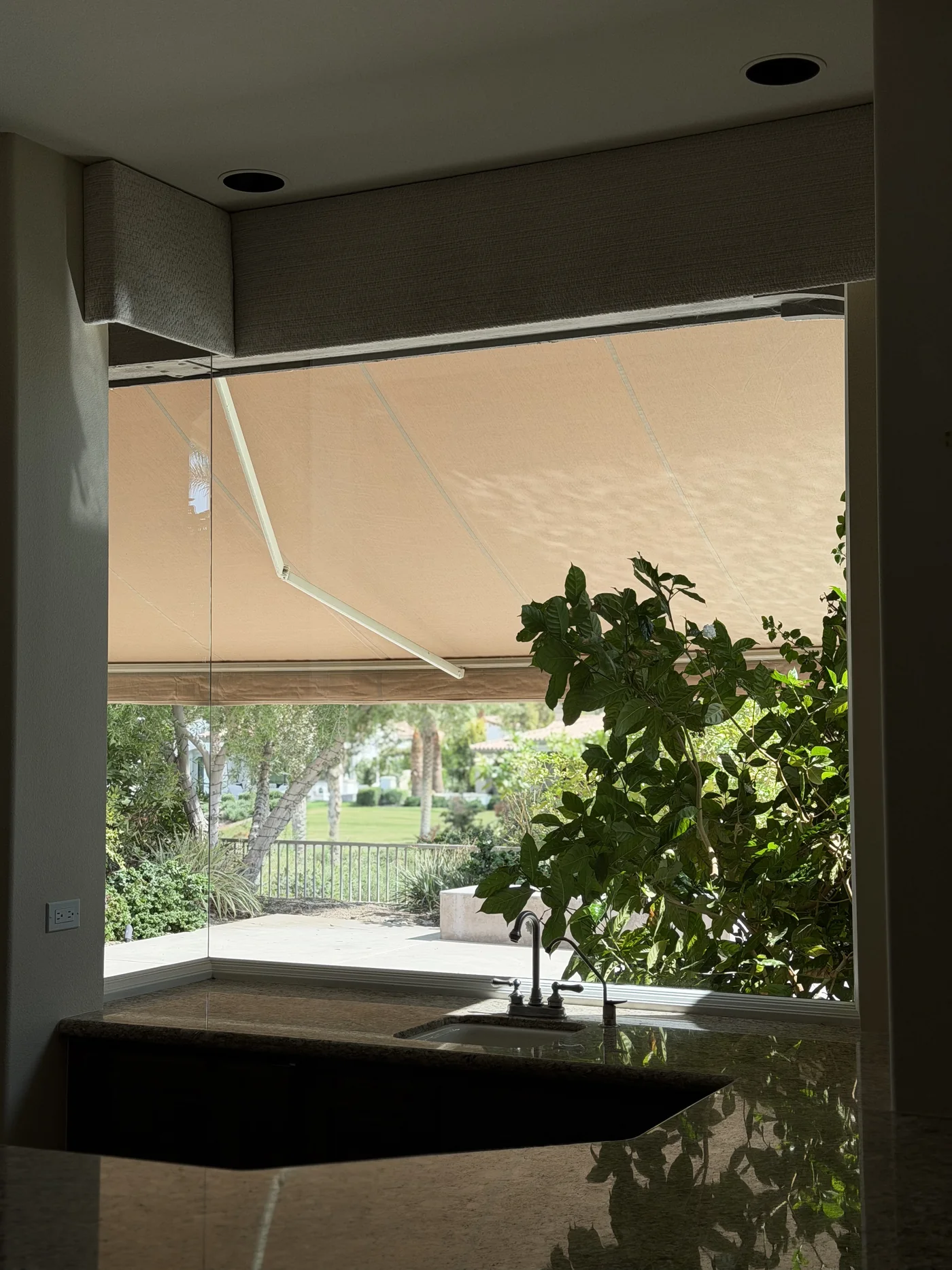 Clear frameless corner window above a granite counter overlooking landscaping at a Toscana Country Club home in Indian Wells