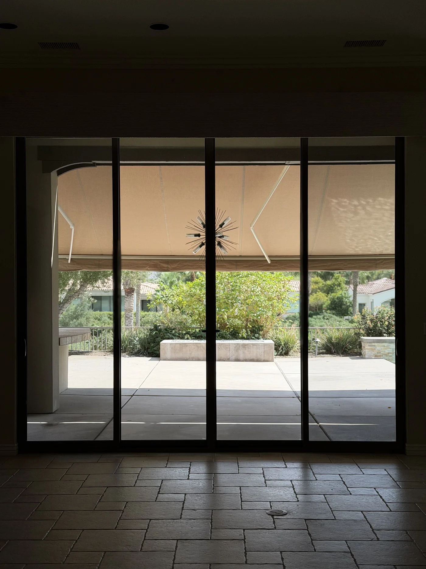 Clean four-panel sliding glass wall opening to a shaded patio and landscaped Toscana Country Club residence in Indian Wells